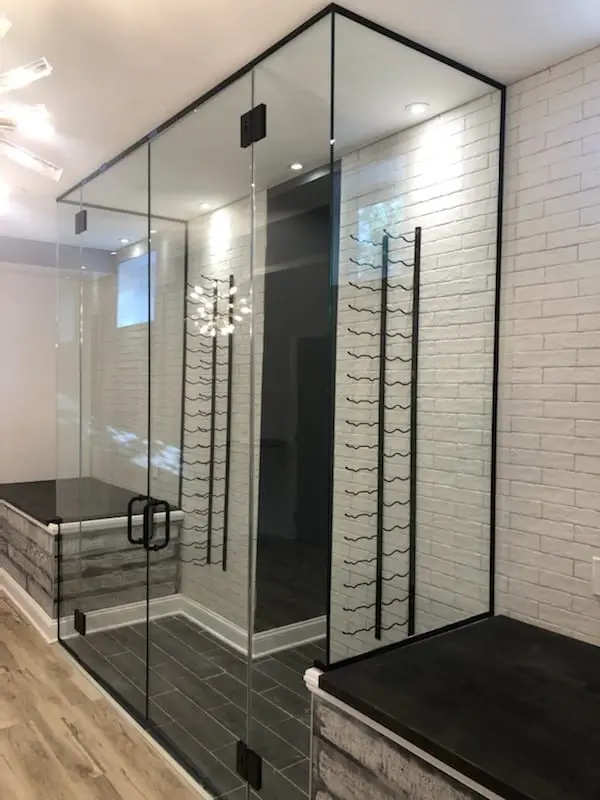 A climate-controlled wine room enclosed in glass, with the racking visible through the panels