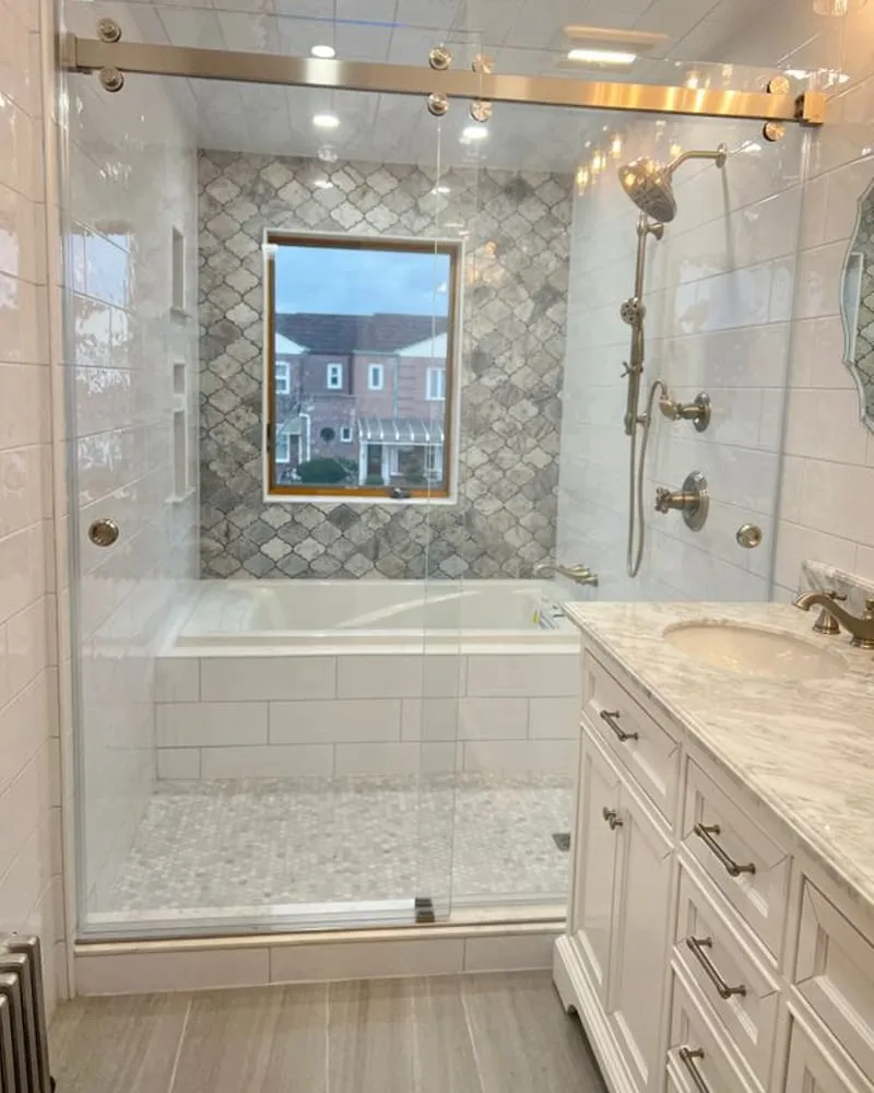 A sliding glass panel on a tub, with scalloped tile above and a marble vanity alongside